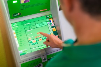 Joueur faisant un pari hippique au distributeur automatique.
